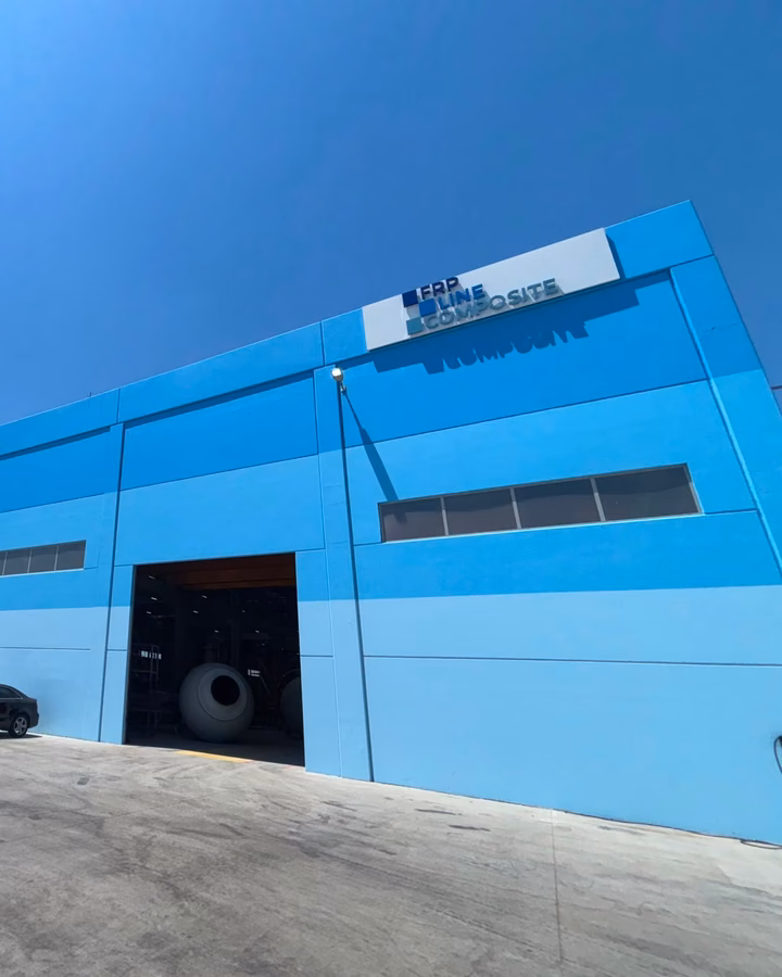 Mavi fabrika cephesini, açık yükleme girişini ve FRP Line Composite tabelasını çapraz açıdan gösteren görünüm
